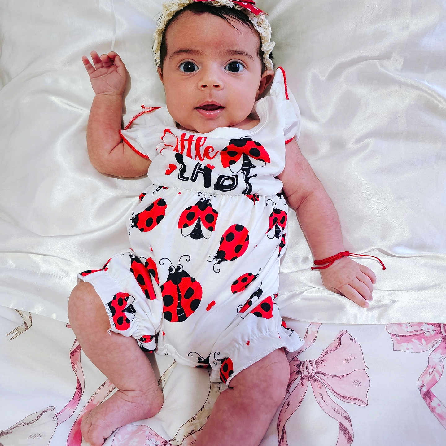 Amelia joined the competition — help win amazing prizes! baby, bed, child, clothing, cute, expression, fabric, foot, hand, headband, indoors, infant, ladybug_pattern, laying, portrait, red_bow, skin, soft_texture, white_sheet, wide_eyes