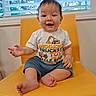 Samuel joined the competition — help win amazing prizes! baby, child, smiling, yellow_chair, tshirt, blue_shorts, barefoot, indoor, window, blinds, greenery, happy, person, cute, sitting, infant, furniture, floor, portrait, natural_light