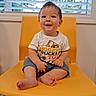 baby, child, smiling, yellow_chair, indoor, window, blinds, shorts, tshirt, barefoot, happy, cute, person, sitting, infant, home, face, portrait, young, furniture