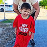 Sabastian is registered to the contest to win money with this photo: child, toddler, woman, smile, red_tshirt, barefoot, outdoor, daylight, pavement, trees, car, joyful, oversized_clothing, walking, grass, happy, casual, person, nature, park