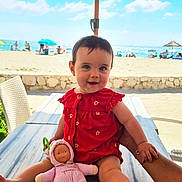 Elena a rejoint le concours — aidez-le/la à gagner de superbes lots ! baby, child, doll, table, hand, beach, umbrella, ocean, sky, clouds, sunny, red_dress, toy, person, outdoor, summer, sand, chair, smile, portrait