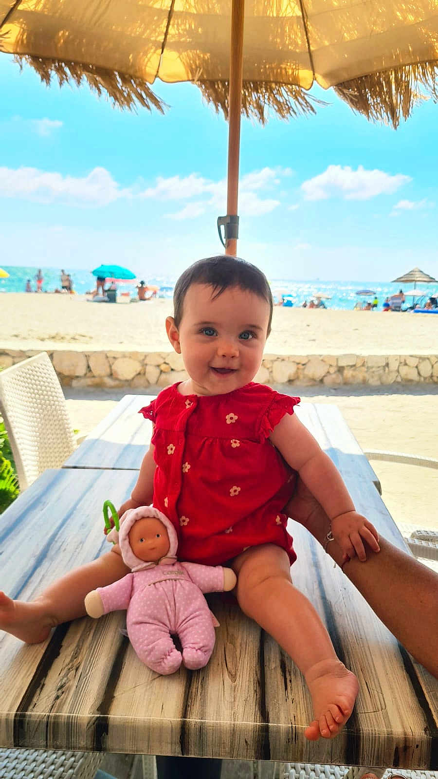 Elena a rejoint le concours — aidez-le/la à gagner de superbes lots ! baby, child, doll, table, hand, beach, umbrella, ocean, sky, clouds, sunny, red_dress, toy, person, outdoor, summer, sand, chair, smile, portrait