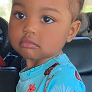 Myla joined the competition — help win amazing prizes! child, toddler, face, blue_shirt, hair_tie, earring, car_seat, vehicle_interior, curly_hair, cute, portrait, young_child, expression, sitting, bright_colors, cartoon_print, flower_pattern, skin, person, indoors