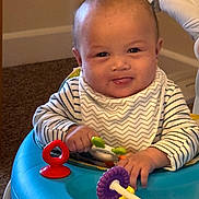 Enzo joined the competition — help win amazing prizes! baby, child, infant, play, toy, activity_center, blue, red, purple, striped_clothing, bib, indoor, carpet, smiling, tongue_out, person, cute, happy, young, hands