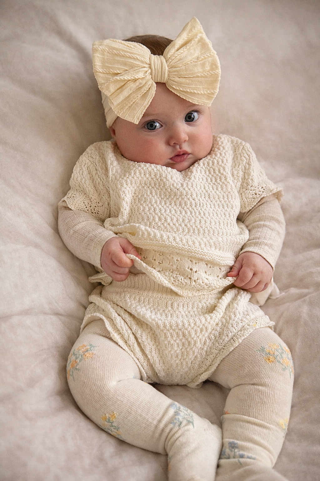 Elara-Alma is registered to the contest to win money with this photo: baby, infant, headband, bow, knitwear, sitting, blanket, soft, cute, child, portrait, cozy, hands, face, curious, indoor, clothing, baby_tights, pattern, expression
