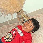 Matteo a rejoint le concours — aidez-le/la à gagner de superbes lots ! child, smiling, red_shirt, super_mario, carpet, indoor, vase, pampas_grass, decor, happy, boy, casual_clothing, floor, home, portrait, playful, hair, face, person, relaxed