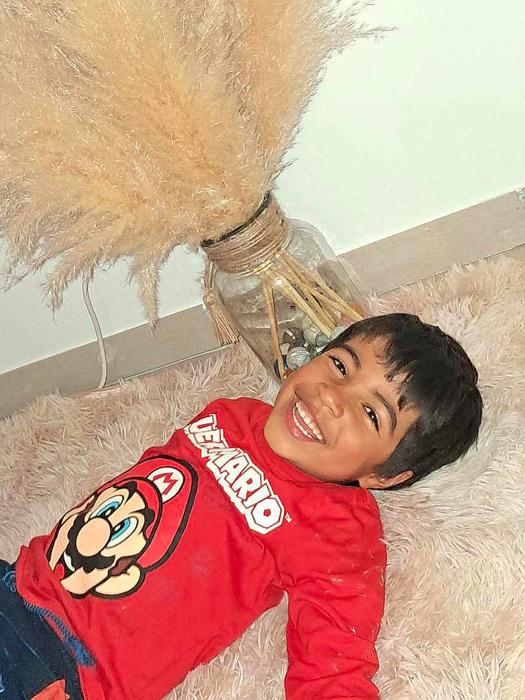 Matteo a rejoint le concours — aidez-le/la à gagner de superbes lots ! child, smiling, red_shirt, super_mario, carpet, indoor, vase, pampas_grass, decor, happy, boy, casual_clothing, floor, home, portrait, playful, hair, face, person, relaxed