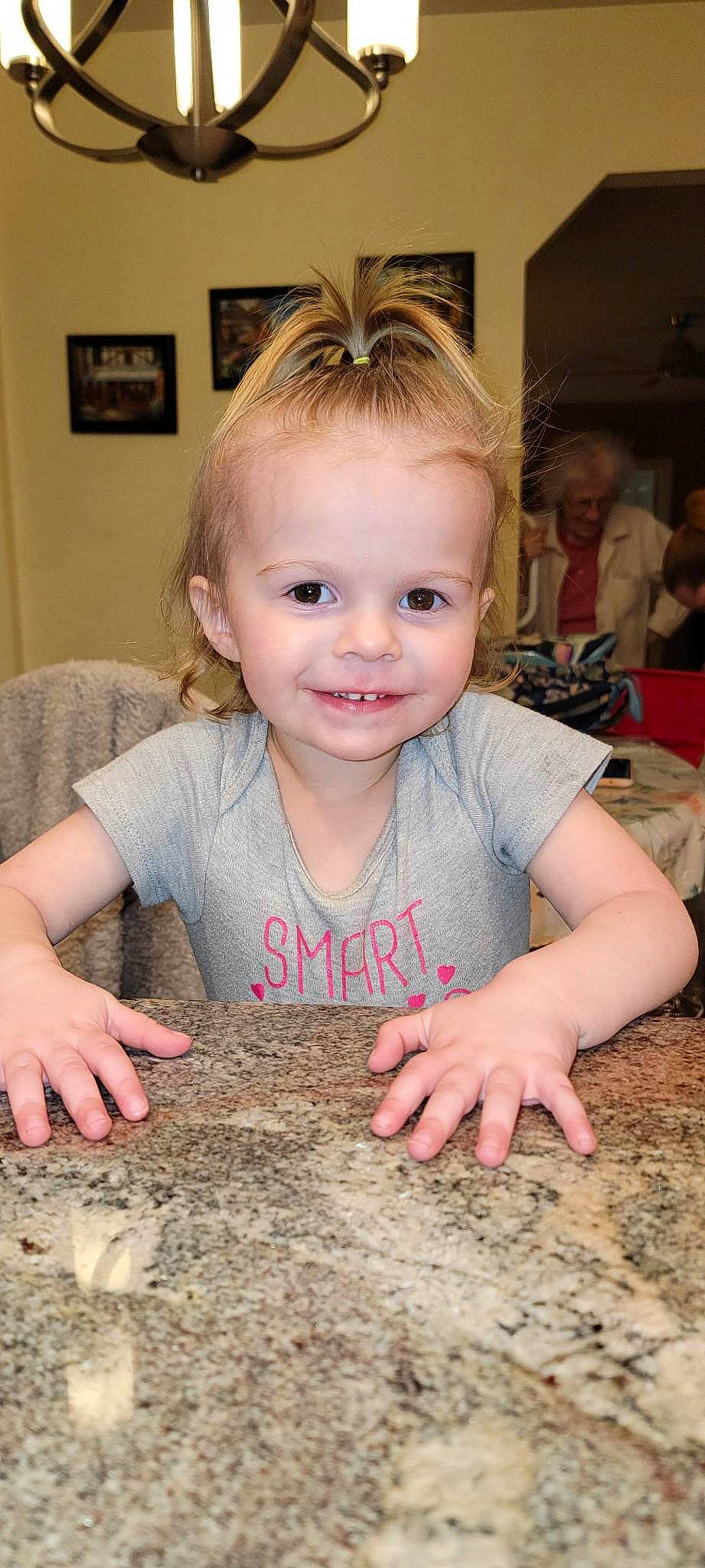 Patricia is registered to the contest to win money with this photo: arm, baby_toddler_clothing, cheek, child, finger, flooring, fun, grass, happy, head, joy, nail, person, picture_frame, sand, sitting, skin, smile, soil, t_shirt