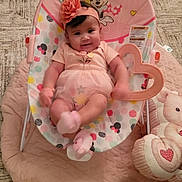 Kindra is registered to the contest to win money with this photo: baby, baby_rocker, carpet, child, colorful, cute, hand, headband, heart_toy, indoor, infant, minnie_mouse, person, pink_clothing, playful, quilt, seated, smartphone, smiling, soft_toy