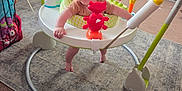 Sonny is registered to the contest to win money with this photo: activity_center, baby, carpet, child, colorful, cute, footwear, fun, furniture, home, indoor, jumper, living_room, person, plastic_toy, playtime, redhead, smiling, sunglasses, toy