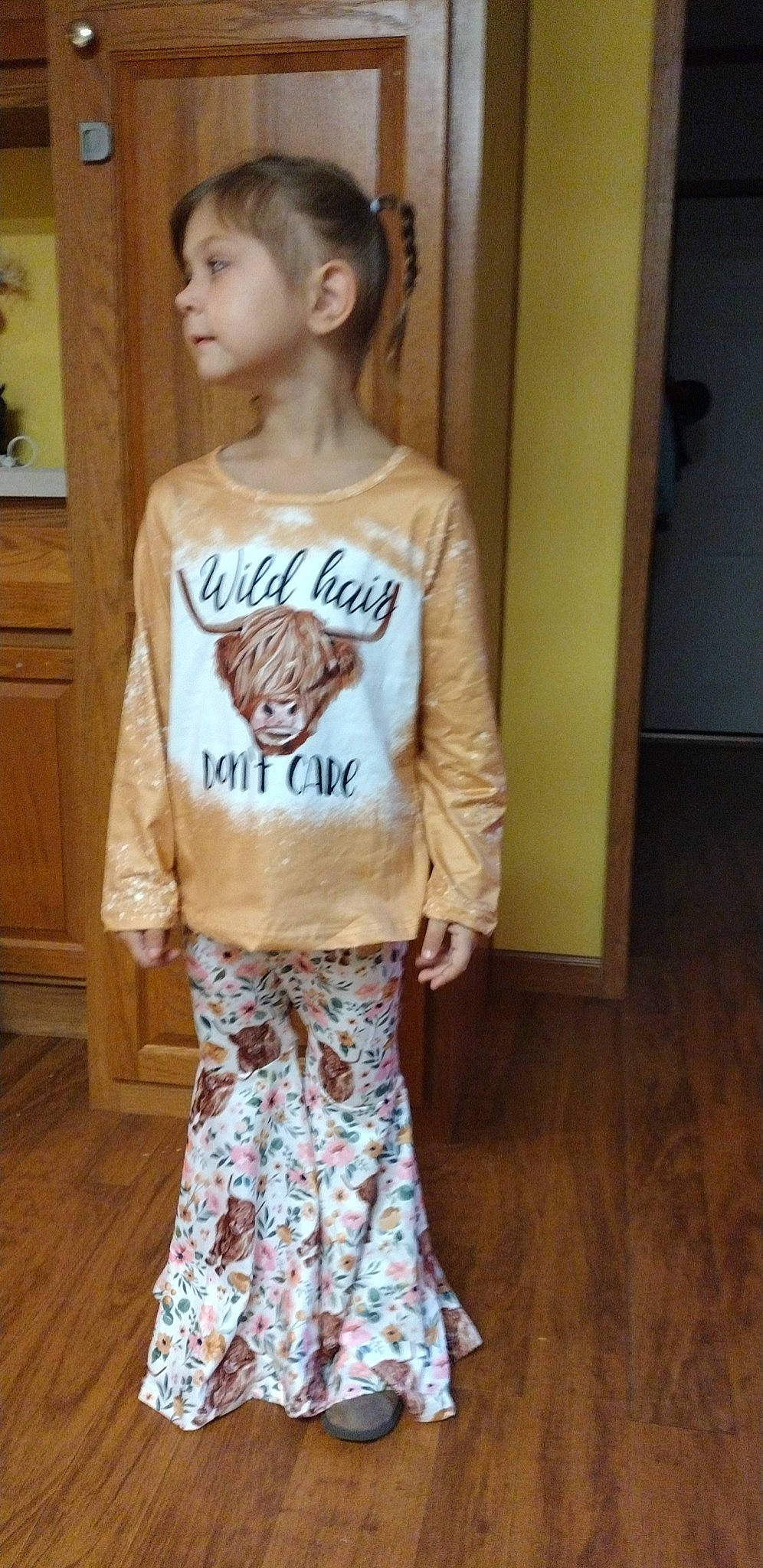 Nadia is registered to the contest to win money with this photo: baby_toddler_clothing, cabinetry, face, fashion, fashion_design, fawn, hardwood, head, long_hair, neck, outerwear, person, shoulder, sleeve, standing, t_shirt, textile, toddler, trunk, waist