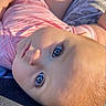 baby, blue_eyes, close_up, infant, pink_clothing, striped_outfit, face, skin, head, hand, sunlight, shadow, portrait, lying_down, child, outdoor, curious, soft_light, person, young