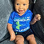 toddler, child, smiling, curly_hair, blue_shirt, under_armour, black_shorts, white_socks, couch, gray_couch, indoor, happy, seated, person, young_child, cute, portrait, baby, comfortable, living_room