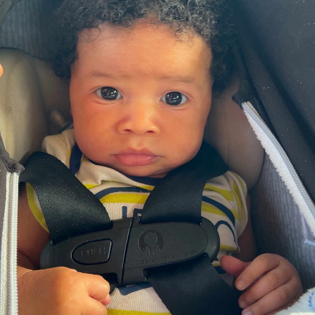 Yahson Mayberry joined the competition — help win amazing prizes! baby, blanket, car_seat, child, closeup, clothing, curly_hair, cute, expression, face, hand, harness, indoor, infant, person, portrait, safety, seat, straps, young