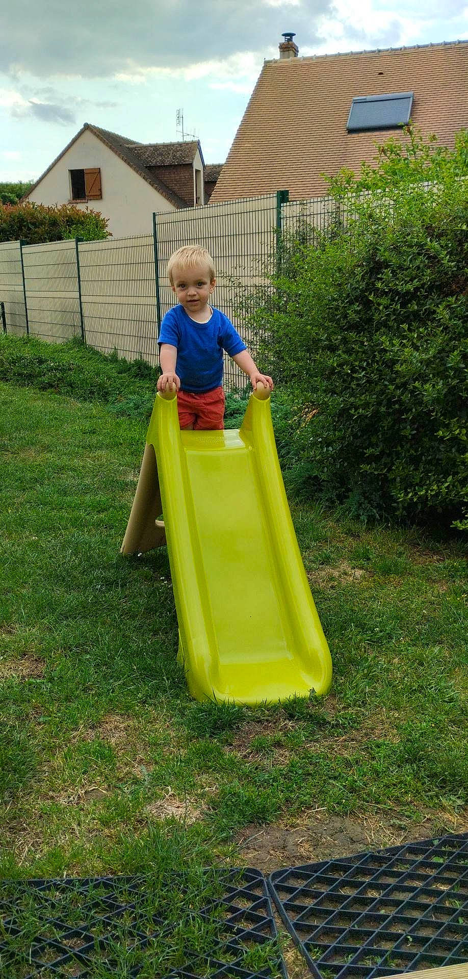 Timothé participe au concours pour gagner de l'argent avec cette photo : baby_toddler_clothing, child, chute, city, fun, grass, house, leisure, outdoor_play_equipment, person, plant, playground, playground_slide, recreation, sky, smile, t_shirt, toddler, tree, window