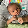 baby, infant, child, blanket, baby_seat, pattern, rainbow, monkey, elephant, bird, clothing, hand, face, head, expression, furniture, indoor, comfort, resting, curious
