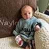 baby, infant, child, sweater, pants, patterned_clothing, chair, blanket, cozy, indoor, cute, seated, portrait, blue_sweater, plush_fabric, curious_expression, small_hands, footwear, soft_lighting, home