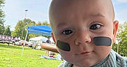 Crue joined the competition — help win amazing prizes! baby, child, infant, portrait, face, eyes, eye_black, outdoor, park, grass, umbrella, sunny, sports_event, tent, picnic, clothing, bib, striped_shirt, sitting, closeup