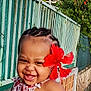 Yuhanna participe au concours pour gagner de l'argent avec cette photo : child, toddler, smile, laughing, hibiscus_flower, red_flower, braids, portrait, outdoor, garden, railing, wall, sleeveless_dress, patterned_clothing, happy, cheeks, teeth, sunlight, closeup, cute