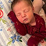 Charleigh joined the competition — help win amazing prizes! baby, newborn, sleeping, infant, pillow, floral_pattern, maroon_clothing, hand, face, closed_eyes, resting, bedroom, cute, soft_lighting, person, cozy, indoor, child, peaceful, young