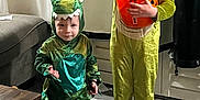 Greyson joined the competition — help win amazing prizes! bucket, child, costume, couch, curtain, cute, dinosaur, face, floor, fun, green, halloween, holiday, indoor, orange, person, playful, shoes, smile, toy