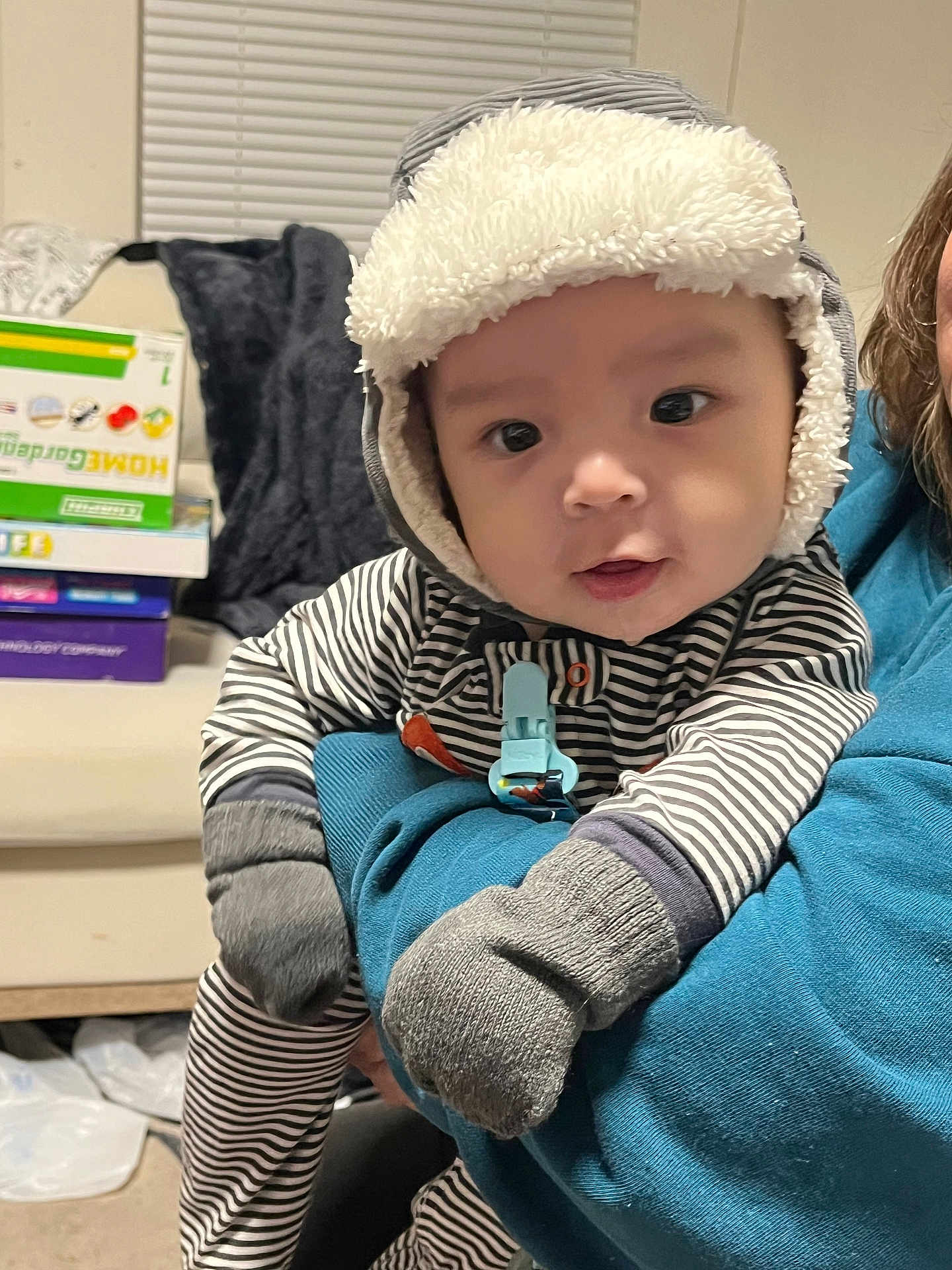 Felix is registered to the contest to win money with this photo: adult, baby, blue_sweater, board_games, casual, child, cozy, curious, cute, furniture, hat, holding, indoor, mittens, person, portrait, soft_lighting, striped_clothing, warm, window_blinds