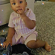 Ari is registered to the contest to win money with this photo: baby, blanket, carpet, child, couch, curious, face, finger_in_mouth, furniture, indoor, living_room, looking_at_camera, pink_clothing, portrait, sitting, smiling, sparkle_effect, striped_shirt, text_overlay, toddler