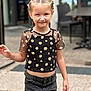 Mia a rejoint le concours — aidez-le/la à gagner de superbes lots ! background_blur, black_top, braided_hair, casual, child, cute, daisy_pattern, daylight, fashion, girl, happy, jeans, outdoor, person, portrait, sidewalk, smile, standing, urban, young