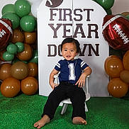 Epoki is registered to the contest to win money with this photo: baby, backdrop, balloons, barefoot, birthday, brown, celebration, chair, child, decorations, first_birthday, football, football_theme, green, indoor, portrait, sitting, smiling, toddler, white