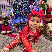 Melinda a rejoint le concours — aidez-le/la à gagner de superbes lots ! toddler, child, christmas_tree, holiday, pajamas, red_clothing, headband, bow, rug, indoor, decorations, lights, santa_claus, figurine, festive, crawling, toy, ornaments, smiling, family