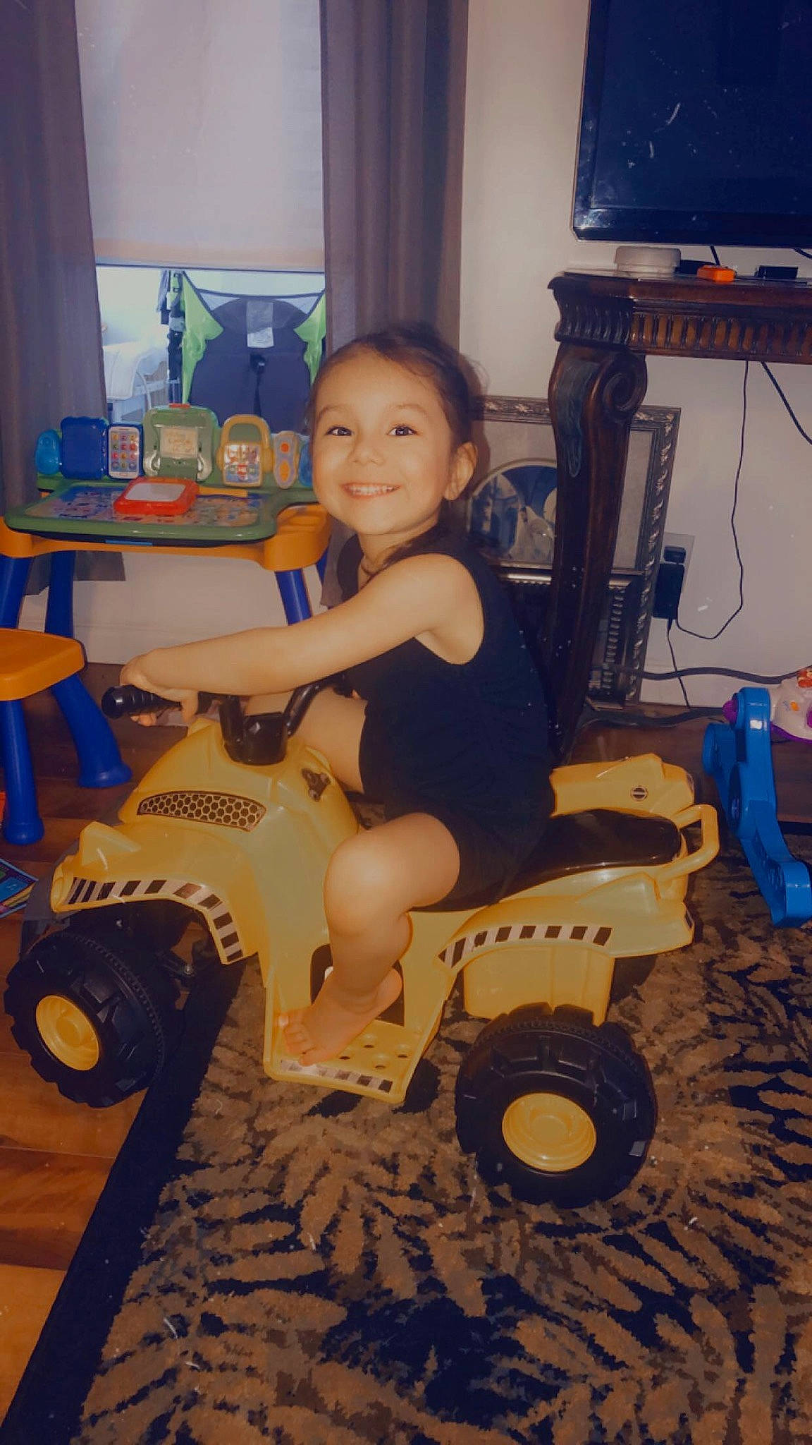 Adalena is registered to the contest to win money with this photo: automotive_tire, automotive_wheel_system, child, curtain, electric_blue, floor, flooring, fun, hardwood, joy, machine, person, riding_toy, smile, tire, toddler, toy, toy_vehicle, tread, vehicle
