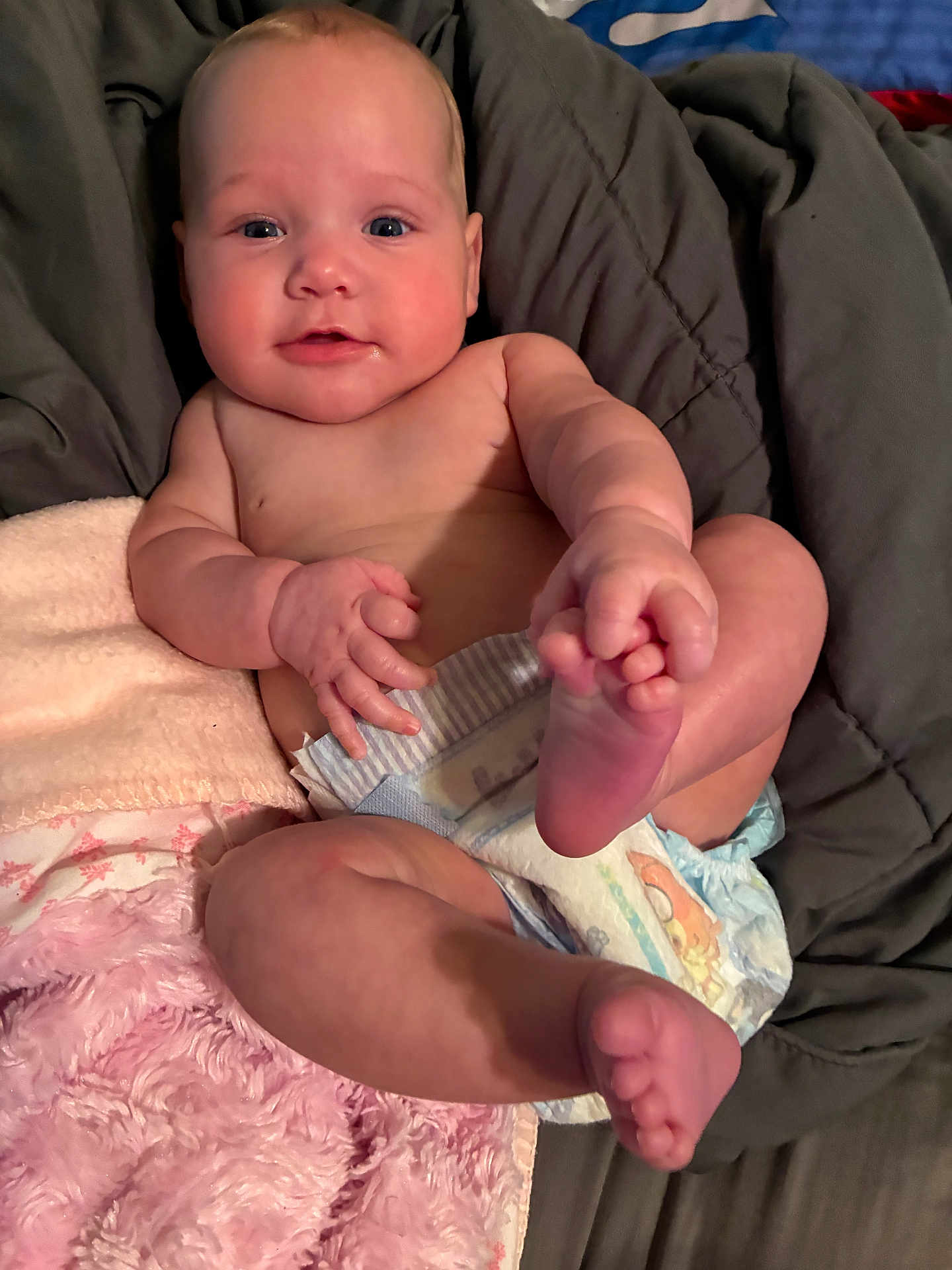 Akira is registered to the contest to win money with this photo: baby, infant, diaper, blanket, bed, skin, foot, hand, cute, child, person, lying, soft, pink, gray, playful, expression, indoors, cozy, touching