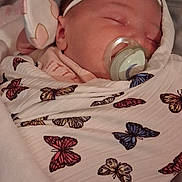 Madison joined the competition — help win amazing prizes! newborn, baby, sleeping, infant, face, pacifier, headband, bow, swaddled, blanket, butterfly, patterned_blanket, bed, bedding, portrait, indoors, cozy, peaceful, closed_eyes, photography