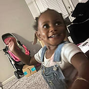 Zaymya is registered to the contest to win money with this photo: cardboard_box, carpet, child, cute, denim_overalls, door, furniture, happy, home, indoor, motion_blur, person, playful, smile, stroller, toddler, toy, white_shirt, window_blinds, young_child