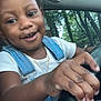 Zaymya is registered to the contest to win money with this photo: car_interior, child, close_up, cute, denim_overalls, dimple, gold_necklace, hand, happy, outdoor_light, person, playful, portrait, seat, smiling, steering_wheel, trees, white_shirt, window, young_child