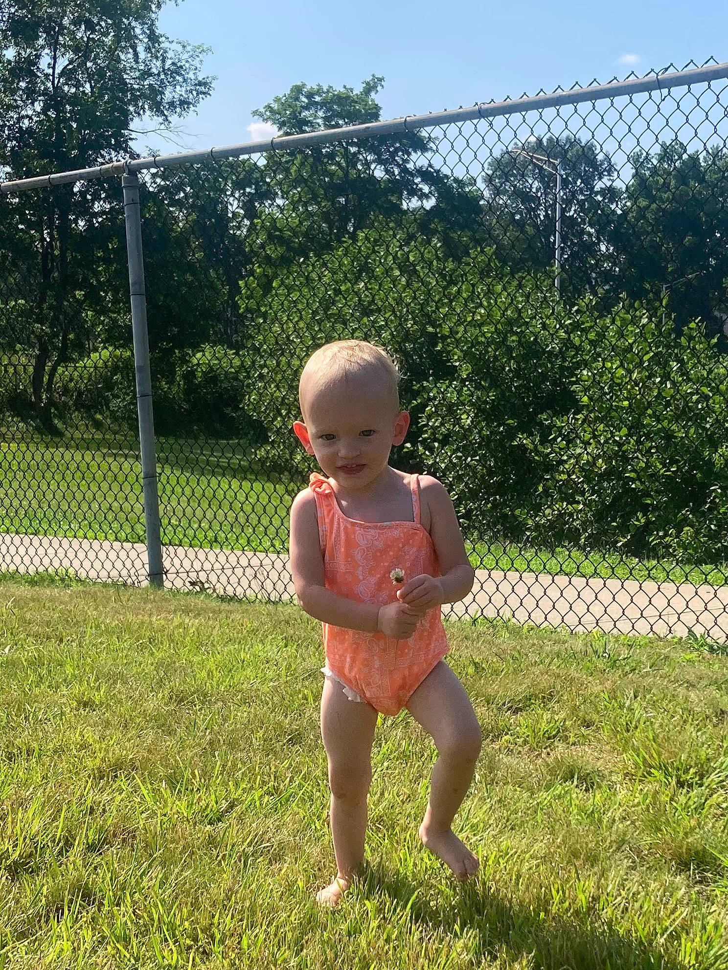 Amaya is registered to the contest to win money with this photo: baby_toddler_clothing, fence, fun, garden, grass, grassland, happy, human_leg, joy, landscape, lawn, leisure, people_in_nature, person, plant, recreation, shrub, sitting, sky, soil