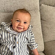Caius joined the competition — help win amazing prizes! baby, child, smiling, striped_shirt, couch, indoor, portrait, happy, cute, face, hand, seated, clothing, infant, person, buttoned_shirt, looking_at_camera, skin, eyebrows, cheeks