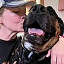 affection, animal, black_dog, cap, closeup, curtains, dog, face, friendship, hand, happy, indoor, kiss, love, person, pet, shirt, smile, tongue, window