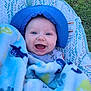 Axton is registered to the contest to win money with this photo: baby, smiling, blue_hat, blanket, marine_animals, outdoor, grass, baby_seat, happy, face, child, infant, cozy, sun_hat, patterned_blanket, cute, portrait, bright_colors, young_child, comfort