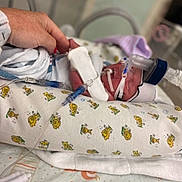 Mackenzie joined the competition — help win amazing prizes! newborn, baby, hospital, medical_equipment, breathing_mask, hand, blanket, cartoon_print, bed, infant, person, pediatric_care, tubes, healthcare, premature_baby, care, love, hospital_bed, rest, tiny