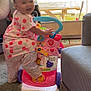 Mackenzie joined the competition — help win amazing prizes! toddler, child, toy, walker, smiling, indoor, dress, pattern, carpet, couch, controller, happy, play, floor, person, furniture, window, light, home, cute