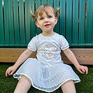 Esmee a rejoint le concours — aidez-le/la à gagner de superbes lots ! child, toddler, girl, pigtails, white_shirt, white_skirt, grass, outdoor, fence, sitting, happy, cute, young_child, portrait, smiling, daylight, casual_clothing, playful, nature, closeup