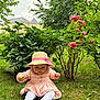 Eline a rejoint le concours — aidez-le/la à gagner de superbes lots ! toddler, child, grass, garden, pink_dress, straw_hat, flower, roses, greenery, bush, outdoor, nature, plants, shoes, hat, sitting, cute, daylight, person, curious