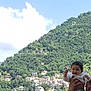 Eline participe au concours pour gagner de l'argent avec cette photo : adult, baby, boat, buildings, child, cloud, dock, greenery, hill, holding, lake, marina, mountain, nature, outdoor, person, sky, smile, trees, water