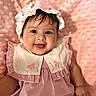 Coraline is registered to the contest to win money with this photo: baby, infant, smiling, pink_dress, bonnet, flower, cute, child, portrait, happy, soft_blanket, textured_blanket, indoors, closeup, adorable, young_child, face, clothing, sitting, cute_expression
