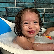Laney is registered to the contest to win money with this photo: toddler, child, bathtub, bath, bubbles, wet_hair, smile, happy, face, water, skin, toy, arm, blue_tiles, indoor, bathroom, cute, playful, person, young_child