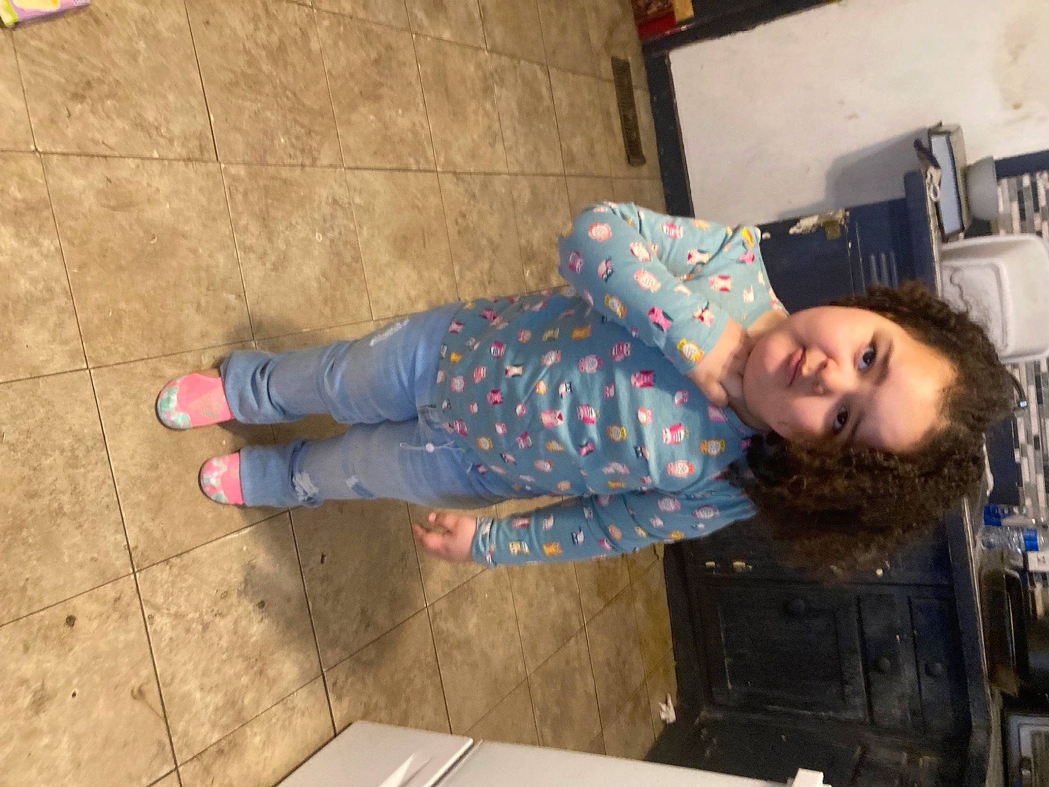 Amiyah is registered to the contest to win money with this photo: child, concrete, denim, floor, flooring, foot, fun, hardwood, human_leg, pattern, person, road_surface, room, sitting, smile, standing, table, walking_shoe, wood