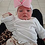 baby, infant, pink_bow, headband, white_sweater, floral_pants, tiled_floor, leopard_print, person, cute, indoors, child, knitwear, newborn, portrait, sitting, looking, cozy, soft_lighting, casual