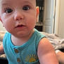 baby, infant, child, face, eyes, blue_clothing, sleeveless, sun_embroidered, curious, indoor, bedroom, door, blurred_background, skin, arm, closeup, portrait, person, young, cute