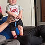 Jaxson is registered to the contest to win money with this photo: baby, child, smiling, hat, tshirt, lee, socks, hands, adult, furniture, recliner, cushion, indoor, living_room, person, portrait, happy, clothing, seated, home